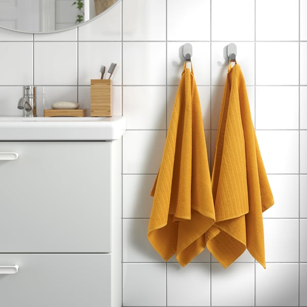 Yellow towels on silver hooks in clean bathroom.