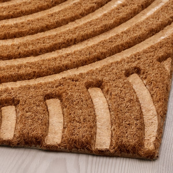 Natural coir door mat with raised wave pattern, durable and textured for grip.
