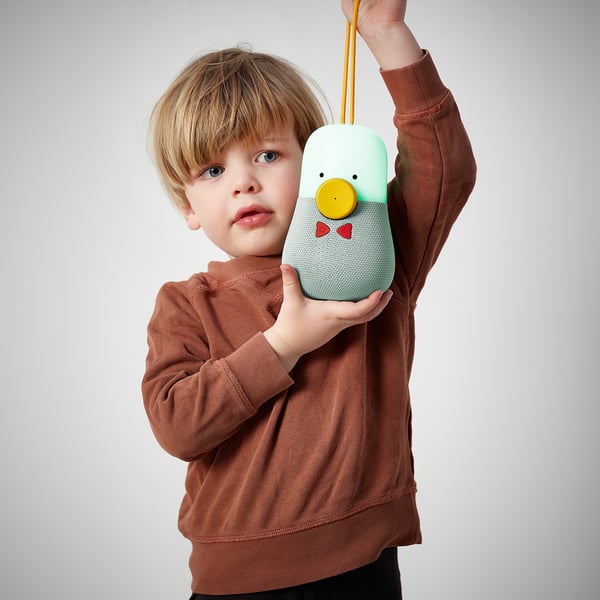 Child holding a colourful, musical toy speaker with light and strap.