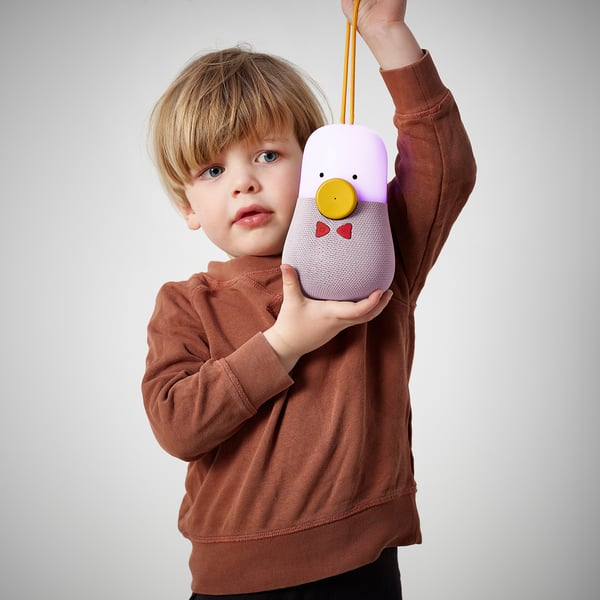 A child holds a colourful, bluetooth speaker with an integrated nightlight and disco light, offering entertainment and serving as a bedside companion.