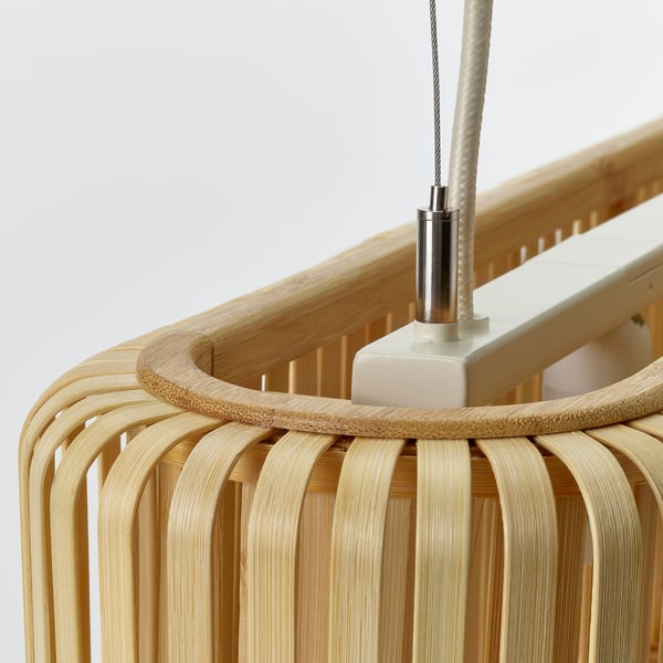 Bamboo pendant lamp shown, hanging from a white ceiling with a stainless steel connector, exhibiting natural wood texture and handcrafted design.