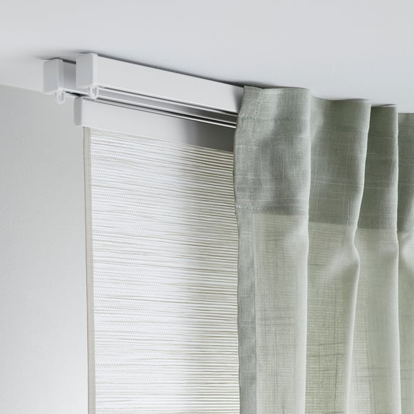 Curtain holder attached to wall with rail and partially drawn curtain.