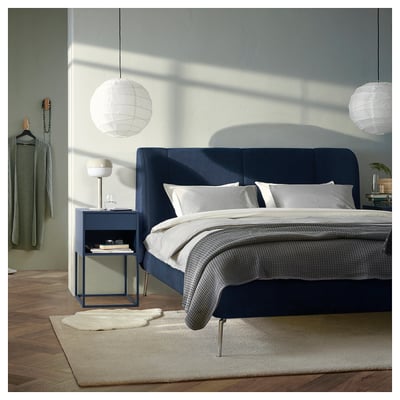 Modern bedroom with blue bed, green sweater, lanterns.