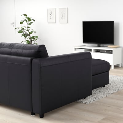 Modern living room with large black leather VIMLE sofa and tv, minimalist decor.