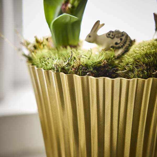 Golden planter with metal texture, holding green moss and small figurines, showcasing high-quality craftsmanship.