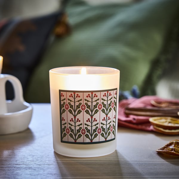 Small VINTERFINT candle in glass, lit; white with green, red holly design.