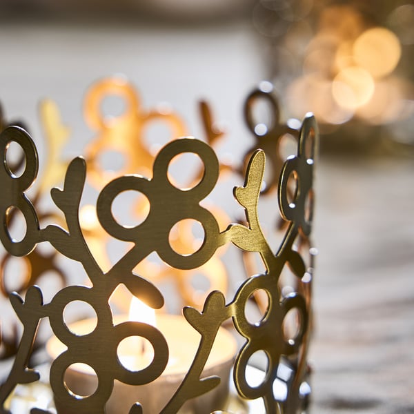Intricate gold metal tealight holder with detailed cutouts, casting warm, cosy light through decorative patterns.