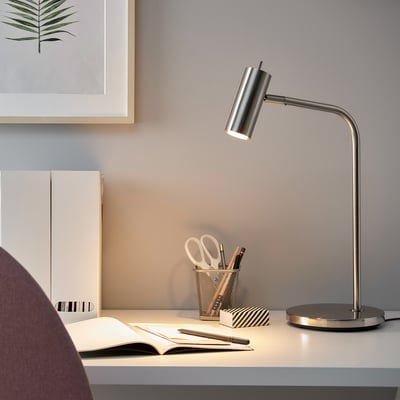 Modern nickel desk lamp, VIRRMO series, adjustable, illuminating workspace with books.