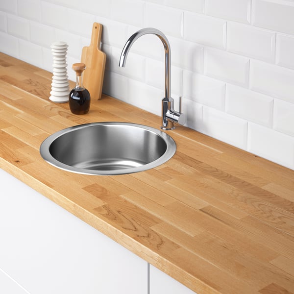 Stainless steel sink with wooden countertop, chrome tap, and kitchen accessories.