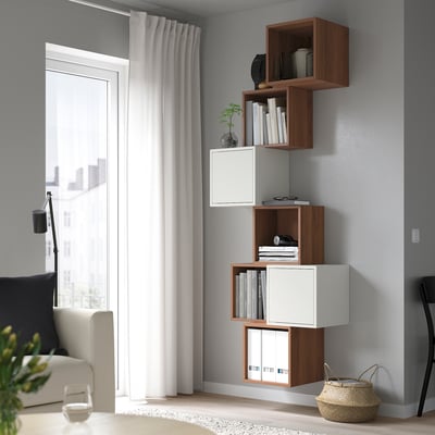 Modern living room with minimalist furniture: EKET shelves, beige sofa, floor lamp, and basket.