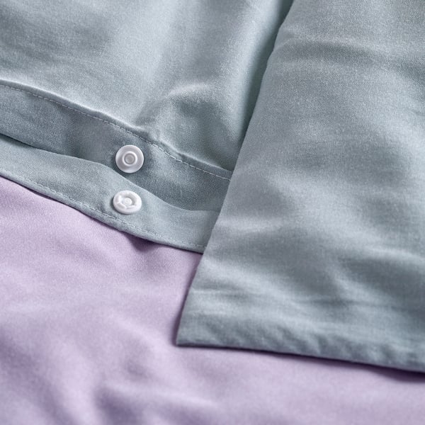 Light blue duvet with buttons and press-stud closure, set on purple bedding.