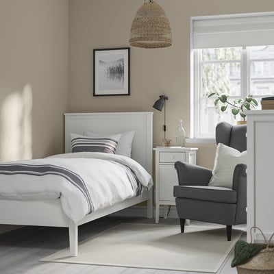 Minimalist bedroom with white GULLABERG bed, blue stripes, grey chair, and pendant light.