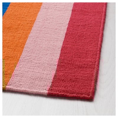 A colourful, handwoven HALVED rug with vertical stripes in various hues, made from wool.