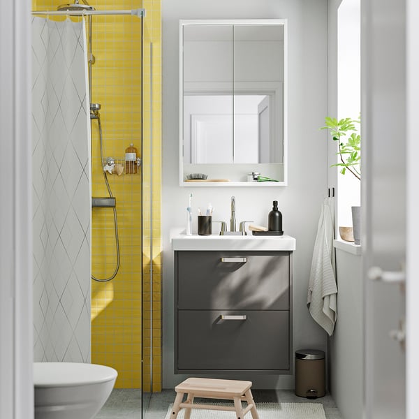 Modern bathroom with yellow-tiled shower, grey HAVBÄCK vanity, marble countertop, mirror cabinet, stool, bin, towel rack, plant.