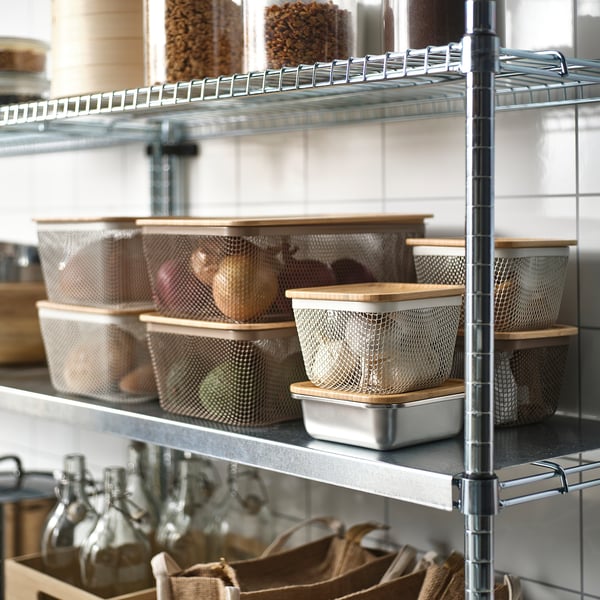 Metal wire rack with mesh baskets storing fruits and vegetables and glass bottles below.