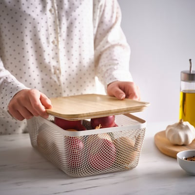 Person places wooden lid on apple-filled mesh basket, IKEA 365+ solution.