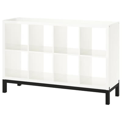 A KALLAX white bookshelf with a black metal base. It has a modern, minimalist design with multiple open shelves.