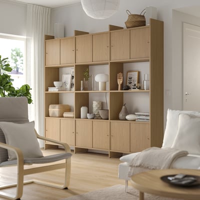 Wooden LÅDMAKARE storage unit with open & closed shelves against wall, displaying decor items & books in a white room.