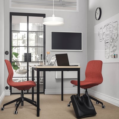 Modern office with two red LÅNGFJÄLL chairs, black table, large window, and whiteboard. Chairs suit rooms sleek, functional design.