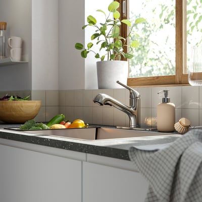 Modern kitchen sink with MACKSJÖN tap, fresh veggies, and houseplant.