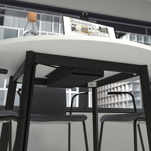 Round black metal base for MITTZON table, with two grey stools, supporting a modern tabletop.