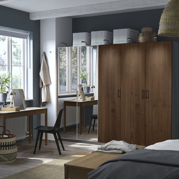Modern bedroom with tall wooden PAX wardrobe, window, desk, and bed.