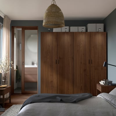 Bedroom with large wooden PAX wardrobe, white bed, grey walls, and a woven pendant light.