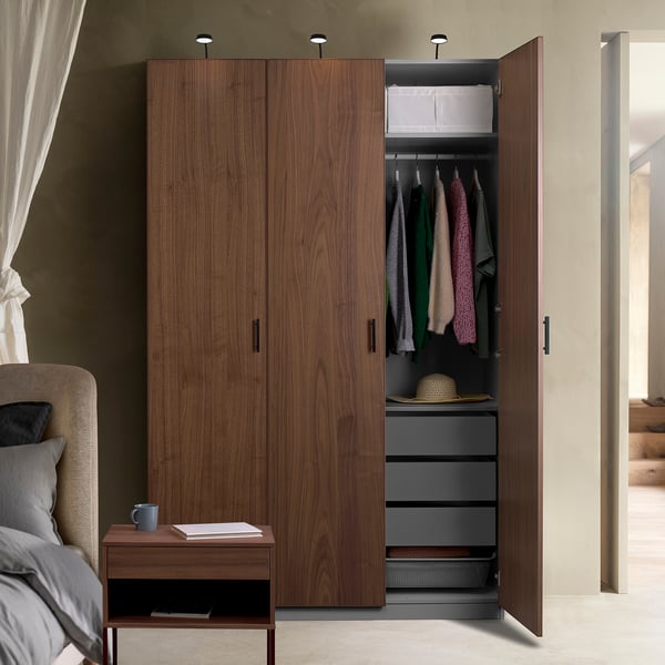 Wooden wardrobe open, revealing clothes, shelves, and storage boxes. Integrated lights highlight the interior.
