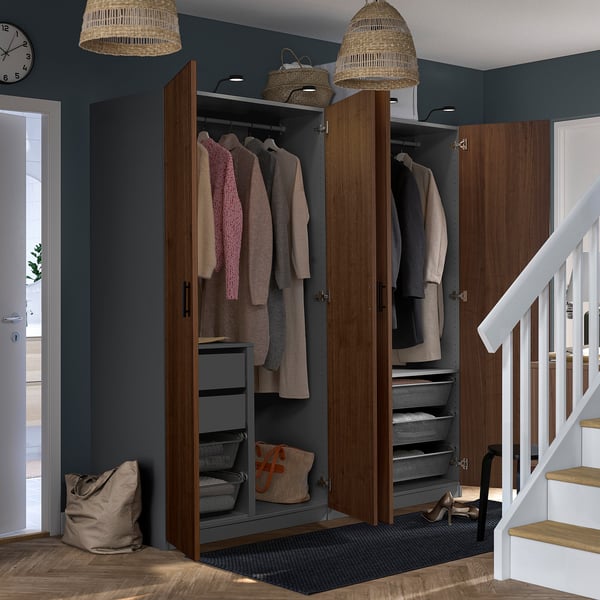 Open closet with coats and shelves, beneath stairs, blue wall.