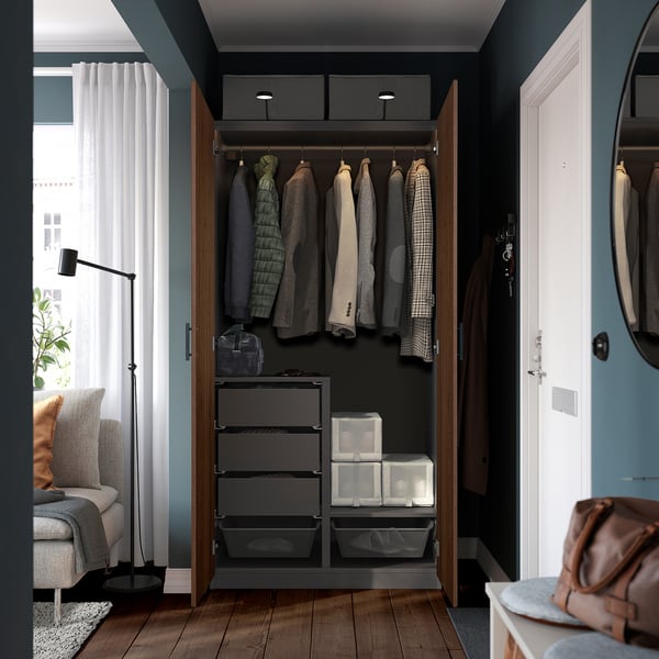 Open wardrobe with clothes, drawers, and boxes, featuring hangers and an overhead storage box.