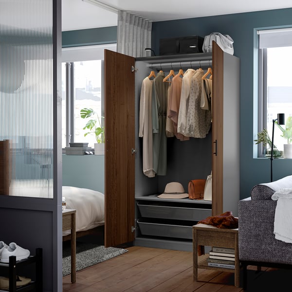 Wardrobe with clothes, hats, bags, grey interior, wooden frame, slow-closing doors, between windows.