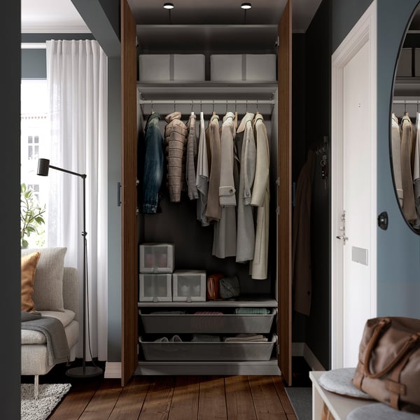 Open wooden wardrobe displaying clothes hangers, storage boxes, and drawers, showcasing organised internal storage of a PAX system.