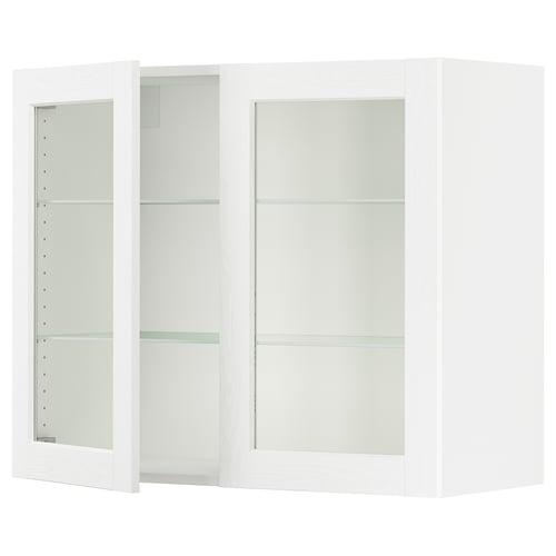 A white SEKTION kitchen cabinet with glass doors and metal hinges, featuring adjustable shelves.
