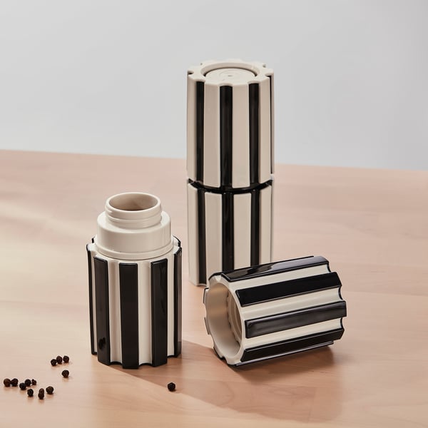 Three striped spice mills, two standing, one with peppercorns.
