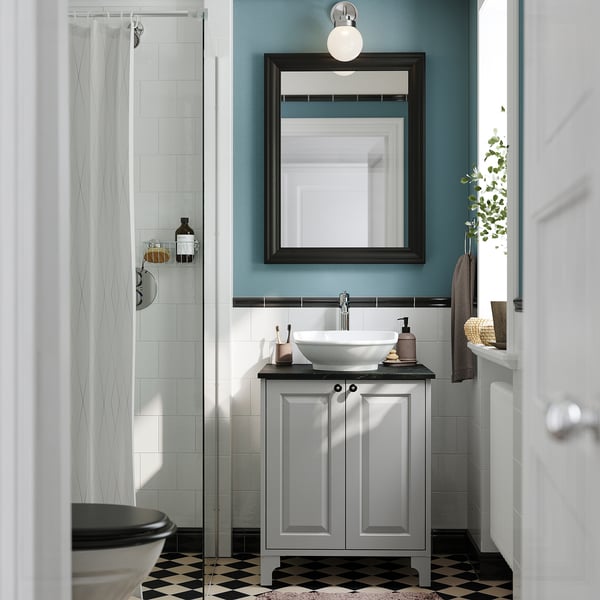 Modern bathroom: grey vanity, white basin, black mirror, blue wall, chequered floor, glass shower.