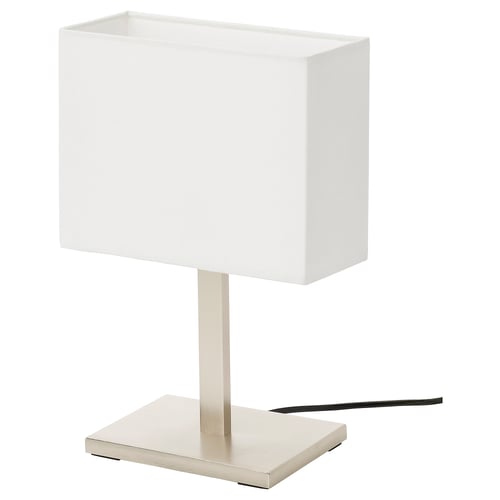 A TOMELILLA lamp with a white shade and silver base. The lamp has a rectangular, modern design with a warm, soft light.