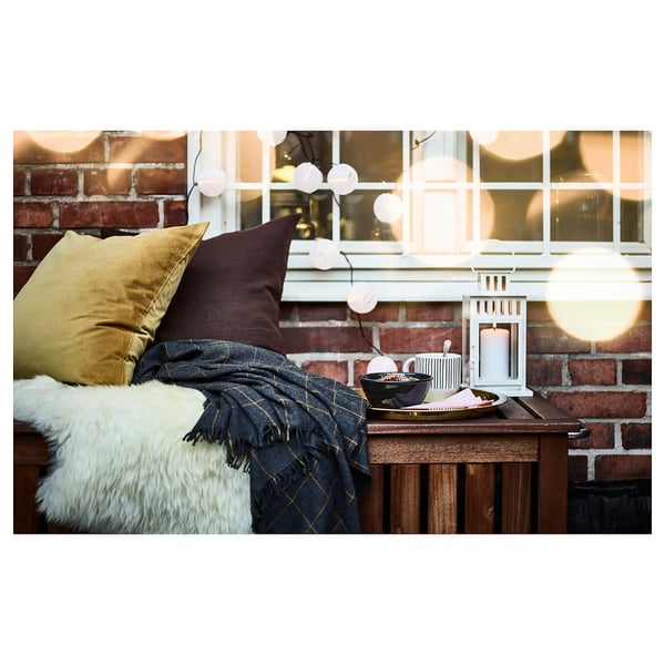 Cosy indoor scene: blue blanket, gold pillows, lantern, and window tray.