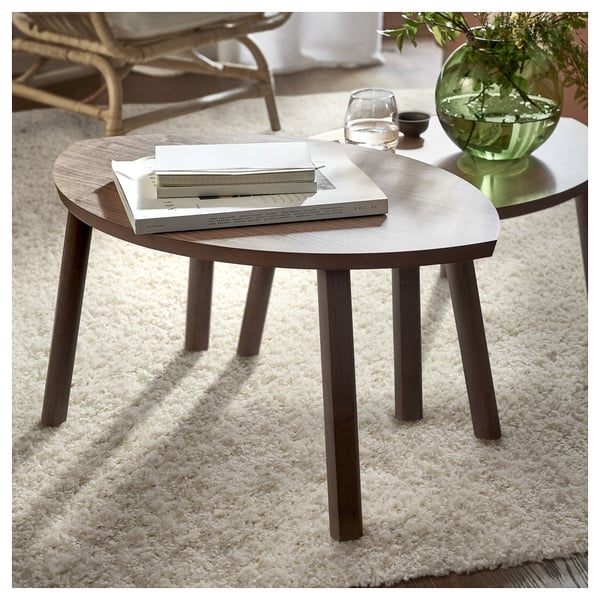 Plush white rug with modern round wooden tables, one holding books, another with a green vase.