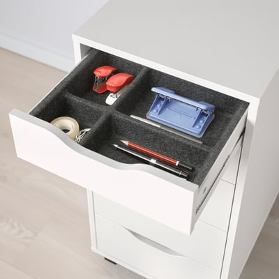 Open white drawer with black felt interior, holding office supplies like stapler, tape, pen, and pencil sharpener.