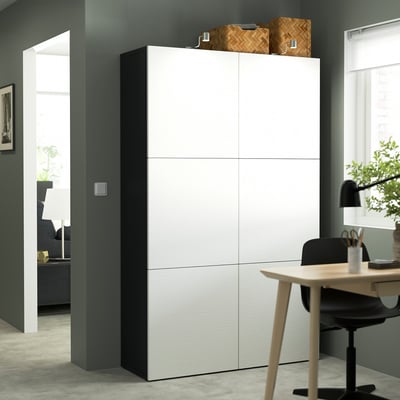 White BESTÅ storage unit with multiple compartments and baskets, wooden desk, sleek modern design.