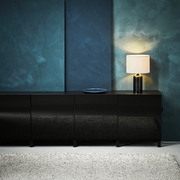Modern room with teal walls, black BESTÅ sideboard, white lamp, textured rug.