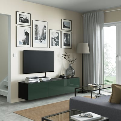 Modern living room with green BESTÅ tv bench, flat screen tv, art, grey curtains, and shelves with books and a vase.