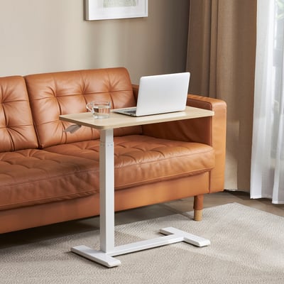 Adjustable laptop table in beige, fits under couch, with melamine top and metal legs. Laptop and mug shown for scale.