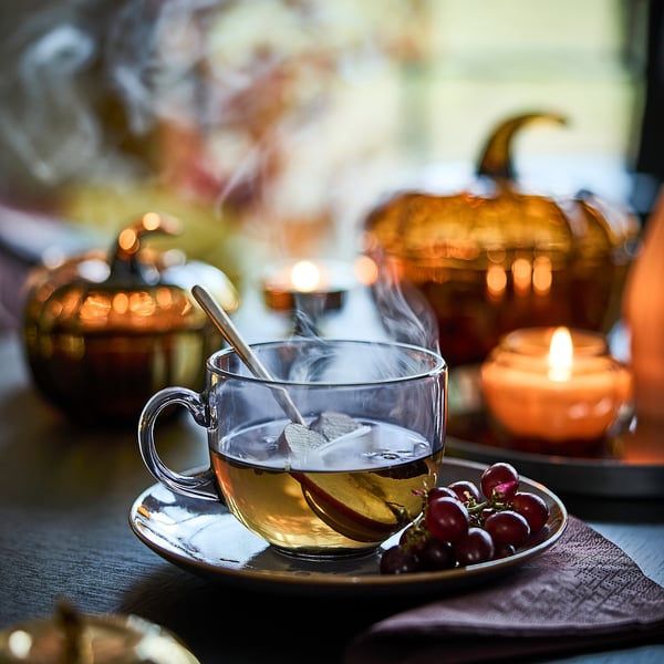 Tea, grapes, pumpkin candles on table.