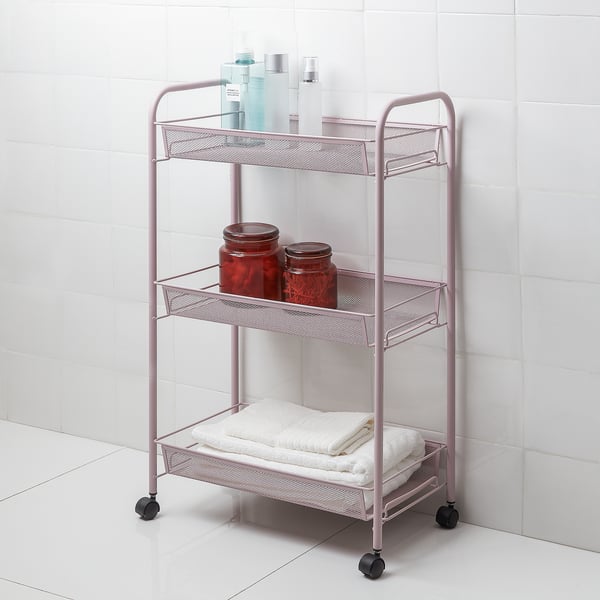 Tier pink metal bathroom trolley with castors, holding towels, jars, & bottles. Compact and mobile.