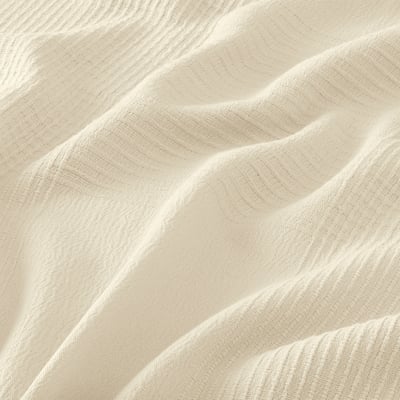 Folded cream-white cotton INDIRA bedspread, textured, for double beds.