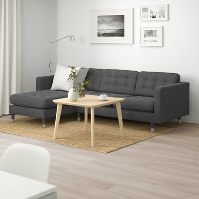 Modern living room with dark sofa, light coffee table, white walls & b&w pictures.