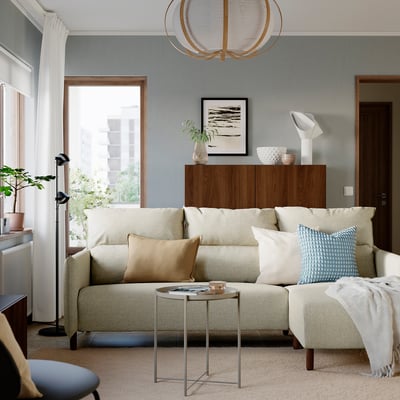 Cosy living room with MANNARP sofa, blue/beige cushions, side table, cabinet, lamp, and large windows.