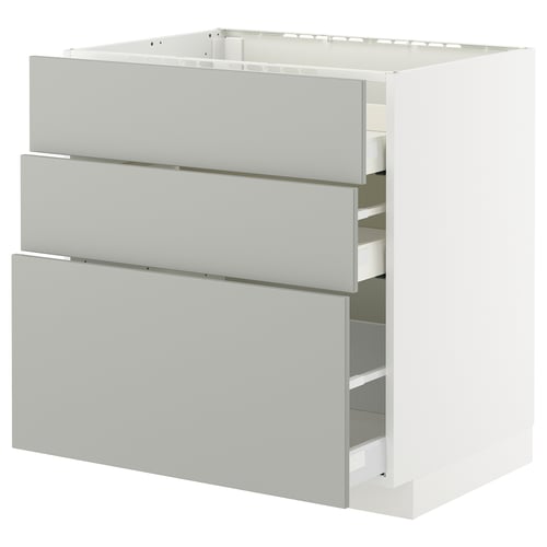 A white IKEA METOD kitchen cabinet with three grey drawers.