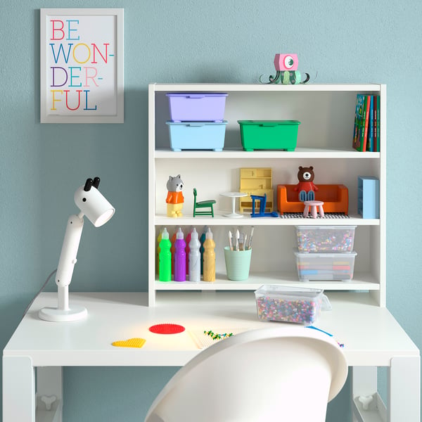 Childs desk setup with white PÅHL desk, colourful storage bins, toys, and a motivational poster.